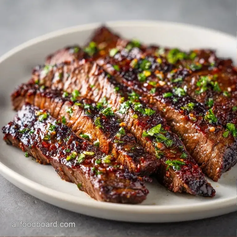 Sliced medium-rare beef strips fanned across a white plate with vibrant grilled asparagus and lemon wedges.