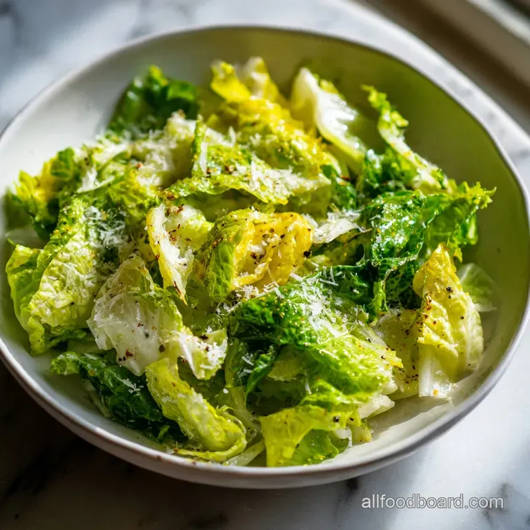 Crisp lettuce leaves piled elegantly on a white plate, sprinkled with vibrant yellow lemon zest.