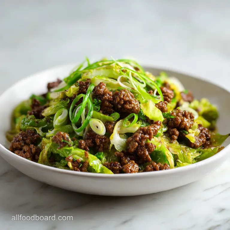 Elegant plating of glazed beef strips and wilted cabbage garnished with toasted sesame seeds and sliced green onions.