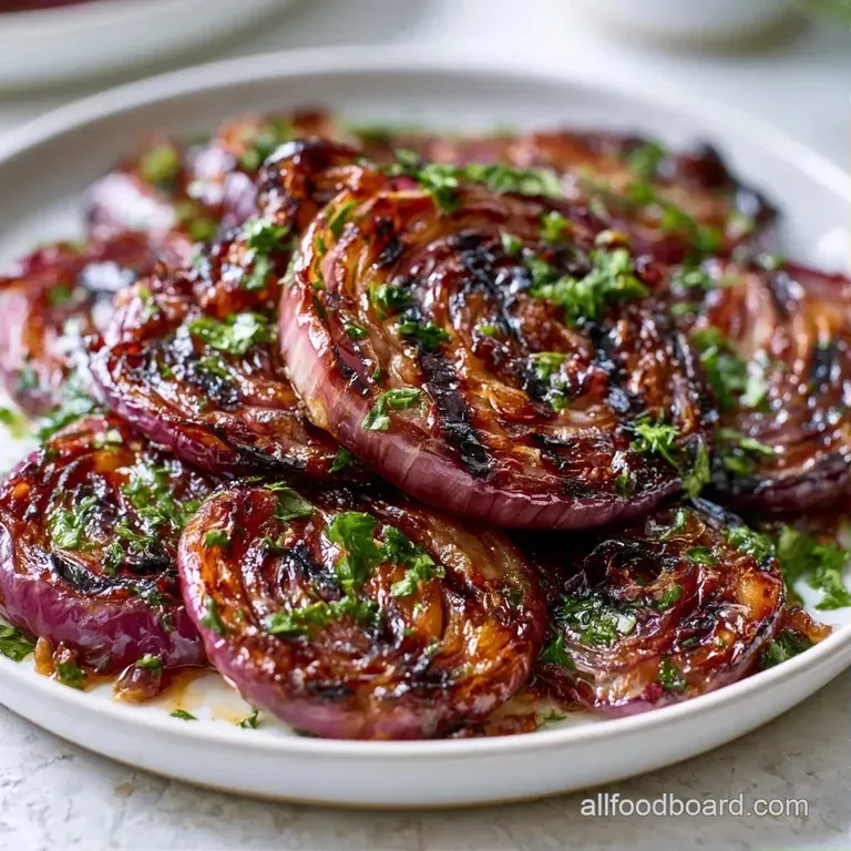 Slices of charred purple onion arranged in a fan shape, garnished with fresh green parsley and a drizzle of oil.